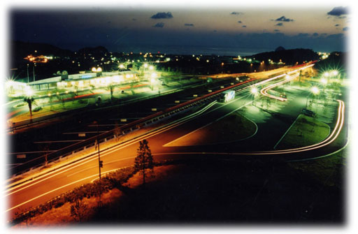 夕暮れの空の下、街灯に照らされた道路の奥に街の明かりが瞬いている夜景の写真