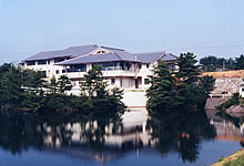 広い池の奥に白い壁の建物がある写真