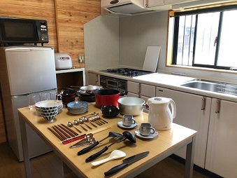 調理器具や食器類が木製のテーブルの上に並べられた台所の写真