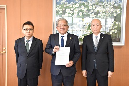 令和4年度の提言書を市長が持ち、その両脇に男性2名が並んでいる写真